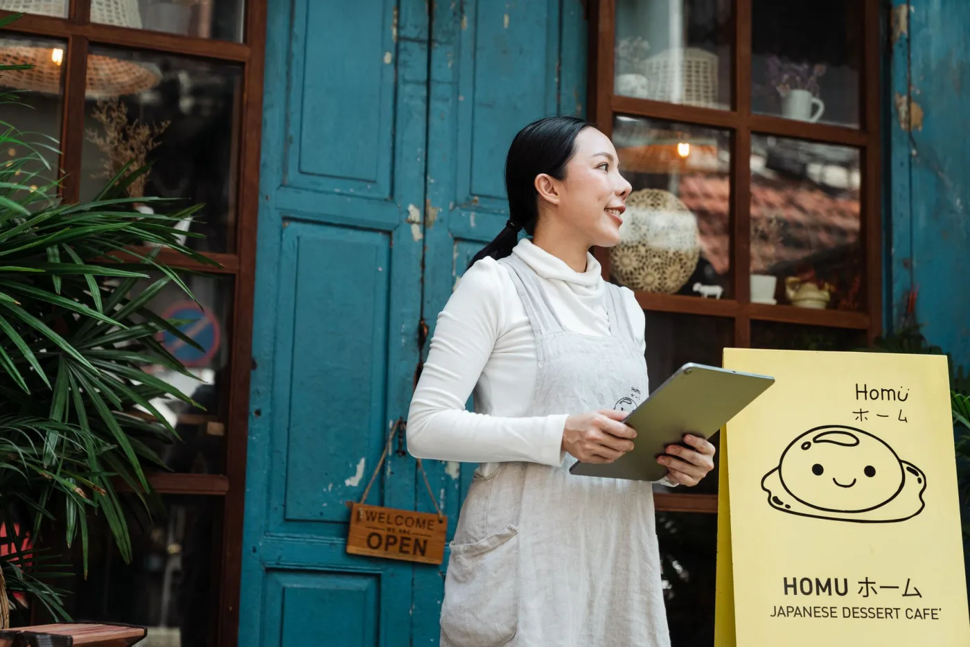A cafe owner using a tablet outside her storefront
