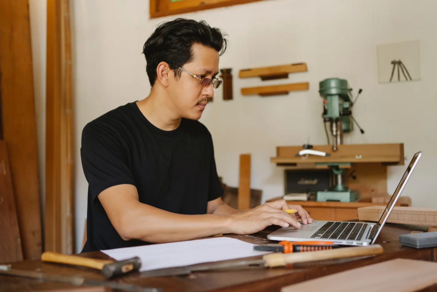 A joiner using a laptop in his workshop